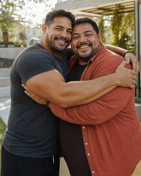 Un hombre musculoso abraza a un hombre de cuerpo grande que sonríe